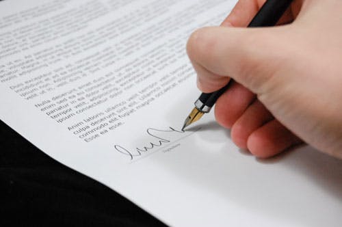 Una persona firmando un documento de un caso relacionado con delitos contra las personas e intereses colectivos